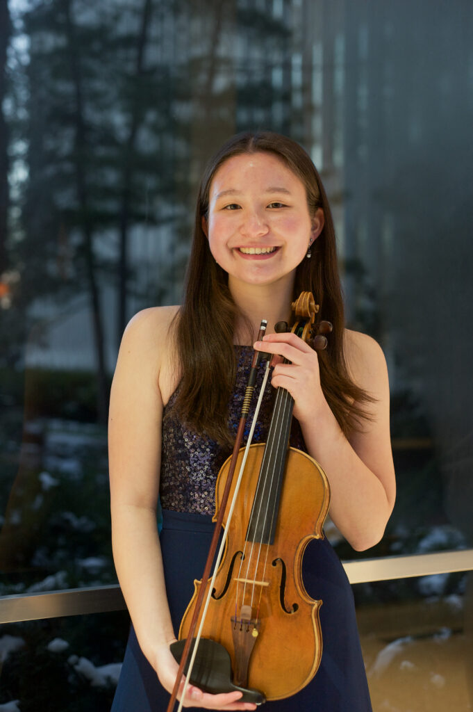 Eleanor O'Brien holding her violin looking happy.